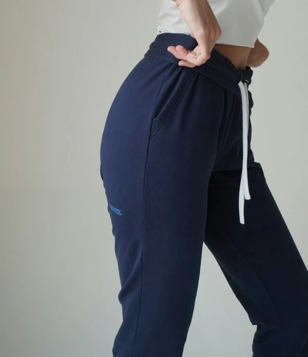 female posing in blue stretchable sweatpants holding phone in back pocket. designed by Humex apparel sweatpants manufacturers